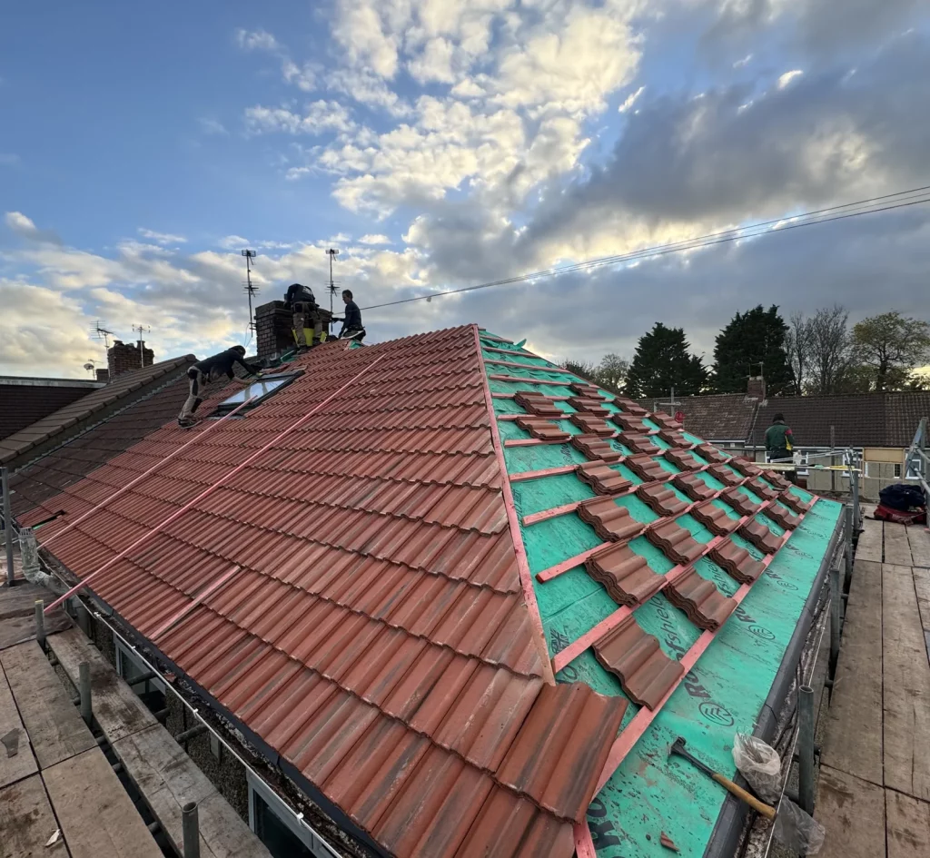 Roofers from Albion Roofing laying new clay tiles on a pitched roof in Claverham Road, Bristol